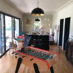 Spacious family living room with piano, foosball table, and large glass doors to the terrace.