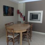 Bright dining room with wooden table and fireplace in a host family home near Grenoble.
