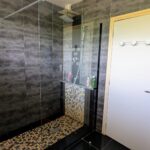 Modern walk-in shower in the shared bathroom of a host family home in Murianette.