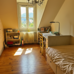 Student bedroom with desk, single bed, and window overlooking the mountains.