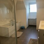 Spacious family bathroom with bathtub, shower, double sink, and modern finishes.