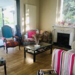 Cozy living room with fireplace, colourful armchairs, and terrace access.