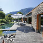Wooden terrace with natural swimming pool and mountain views at a French host family home near Grenoble.